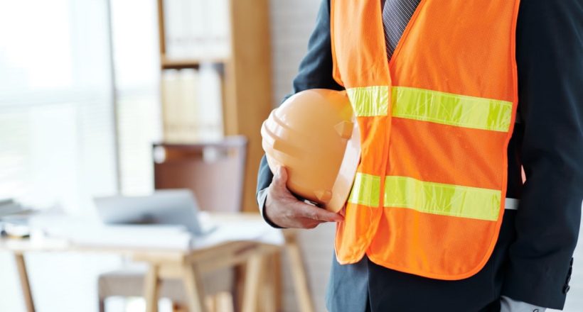 Cropped image of engineer with hardhat standing in office